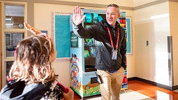 an adult giving a high five to a young student in a school hallway