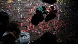 Children on the ground drawing messages of love with chalk sticks