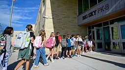 children walking single file into a school