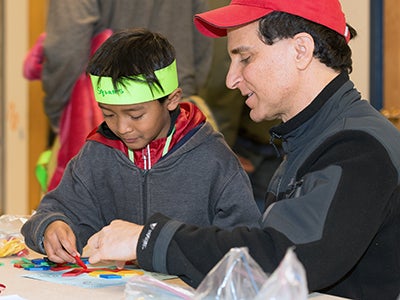 A man working with a young boy at a table A man working with a young boy at a table