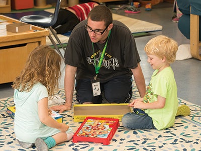 A man working with a young boy and girl playing the Operation game A man working with a young boy and girl playing the Operation game