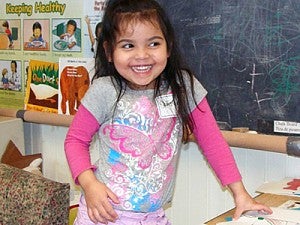 A young girl laughing in a classroom