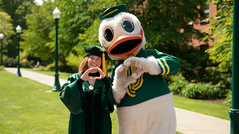 COE graduate posing with the Oregon Duck mascot