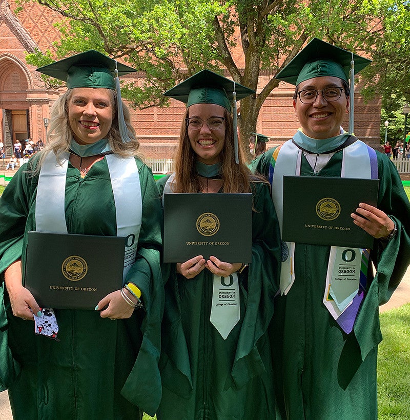 Three UO COE graduates holding diplomas