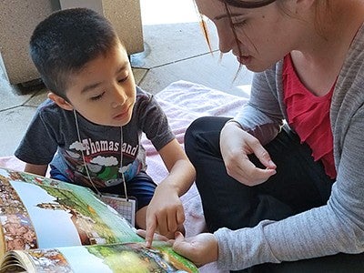 A woman reading a children's book with a young boy